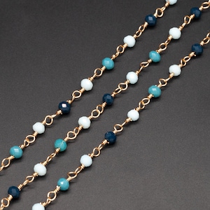 May include: Three strands of gold chain with blue, teal, and white beads.