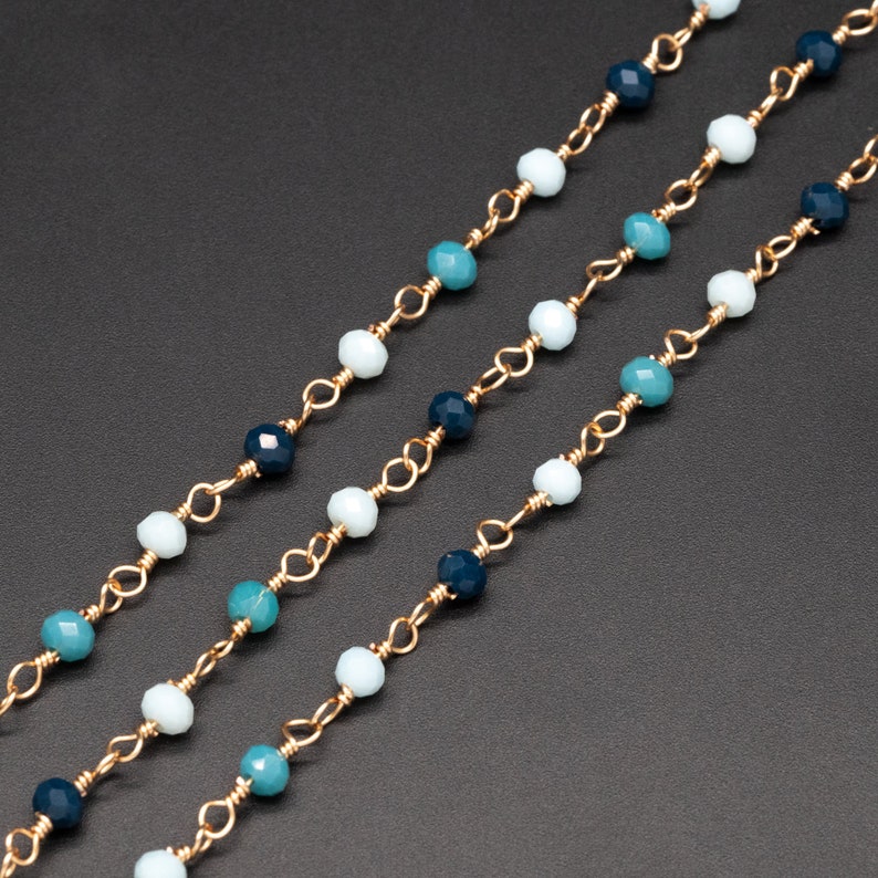 May include: Three strands of gold chain with blue, teal, and white beads.
