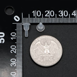 May include: Two clear plastic push-in fasteners, one with a round head and one with a pointed head, are shown next to a US quarter for size comparison.