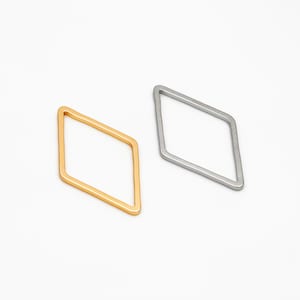 May include: Two diamond-shaped hoops, one gold and one silver, are shown against a white background.