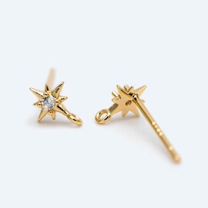 May include: A pair of gold star-shaped earring findings with a small clear rhinestone in the center of each star. The findings have a loop on one end and a post on the other end.