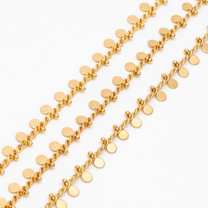 May include: A gold chain necklace with multiple rows of small, round, gold discs hanging from it.