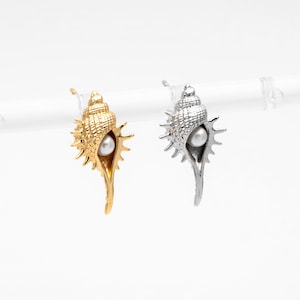 May include: A pair of shell-shaped earrings with a pearl in the center. One earring is gold and the other is silver.