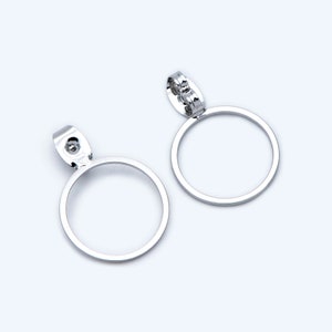 May include: A pair of silver hoop earrings with a simple, circular design. The earrings have a hinged closure.