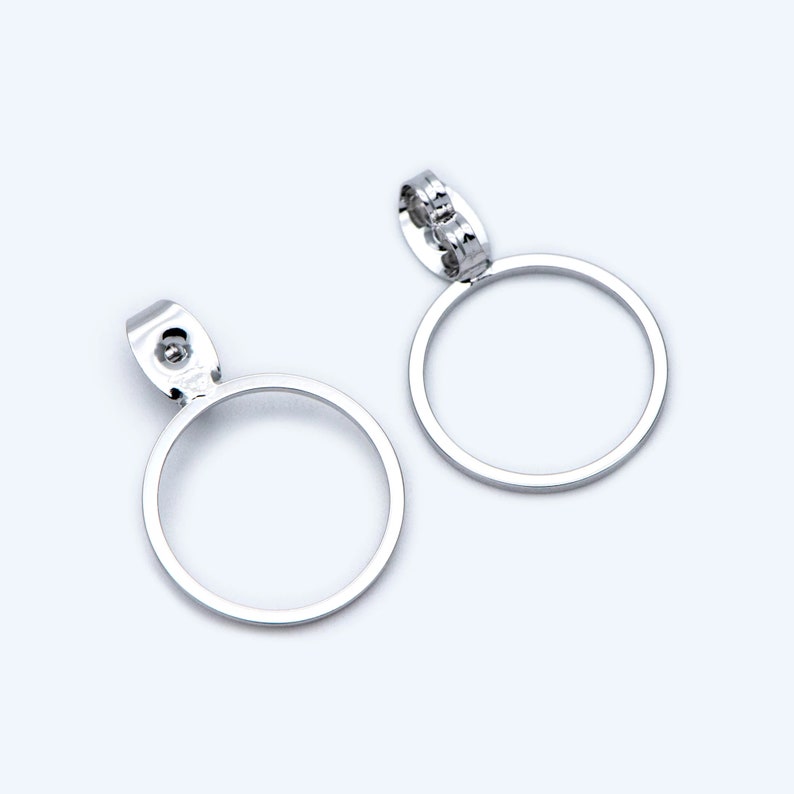 May include: A pair of silver hoop earrings with a simple, circular design. The earrings have a hinged closure.