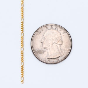 May include: A gold chain necklace with a delicate, flat, oval-shaped link. The chain is laid out next to a US quarter, dated 1979, to show the scale.
