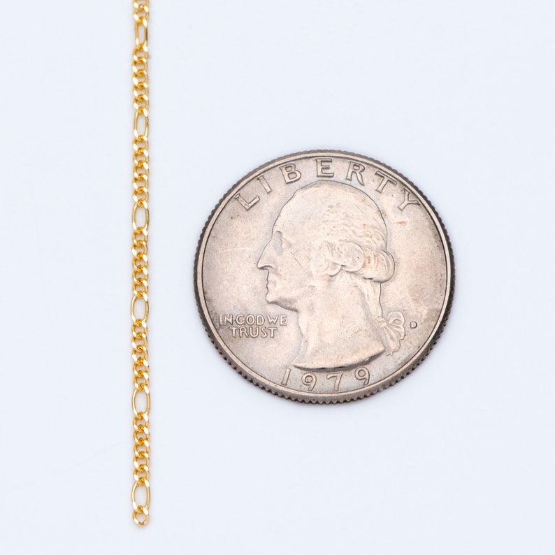 May include: A gold chain necklace with a delicate, flat, oval-shaped link. The chain is laid out next to a US quarter, dated 1979, to show the scale.