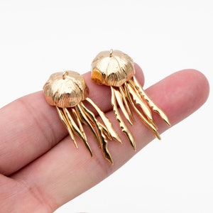 May include: A pair of gold-tone earrings shaped like jellyfish with dangling tentacles.