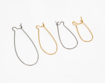 May include: Four earring hoops, two silver and two gold, are arranged in a row on a white surface. The hoops are all the same size and shape, but they are different colours.