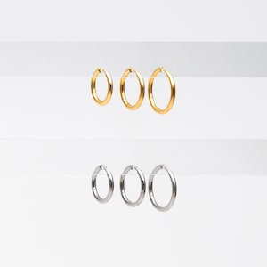 May include: Three gold hoop earrings and three silver hoop earrings displayed on a white background.