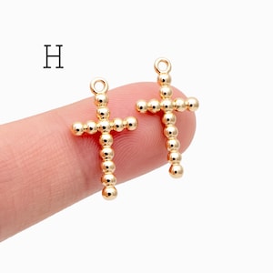 Pu&ograve; includere: Due ciondoli a forma di croce color oro. Ogni croce &egrave; composta da piccole perline rotonde. Le croci hanno un anello nella parte superiore per il fissaggio a una catena o ad un altro componente di gioielleria. La lettera "H" &egrave; nell'angolo in alto a sinistra.