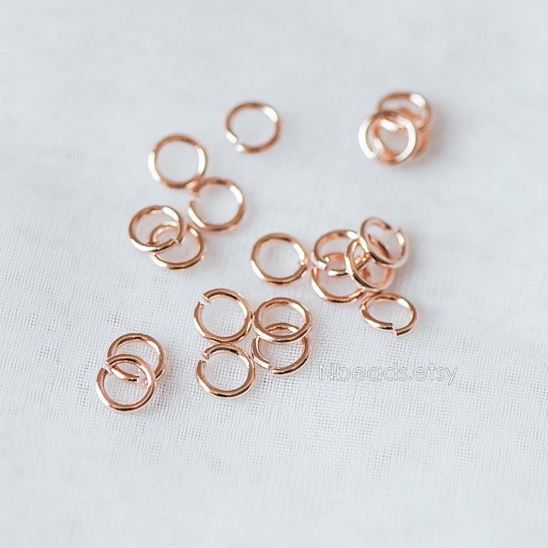 May include: A close-up of a pile of rose gold jump rings. The jump rings are small and delicate, and they are perfect for jewelry making.