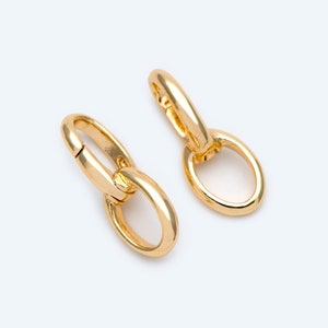 Op de afbeelding: Een paar gouden oorringen met een gekoppeld kettingontwerp.