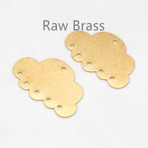 Puede incluir: Dos componentes en bruto de latón en forma de nube con múltiples agujeros para la fabricación de joyas. Los componentes tienen un acabado cepillado y el texto "Raw Brass" se muestra encima.