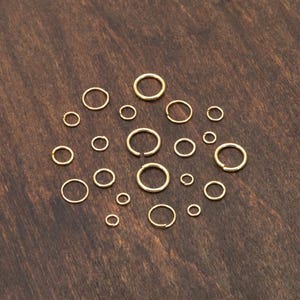 May include: A collection of gold-colored metal hoops of varying sizes, arranged in a circular pattern on a wooden surface.