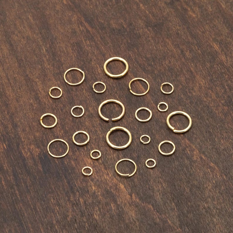 May include: A collection of gold-colored metal hoops of varying sizes, arranged in a circular pattern on a wooden surface.
