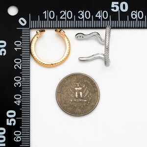 May include: Two gold and silver ear cuffs with a textured surface. The ear cuffs are next to a US quarter for size comparison.