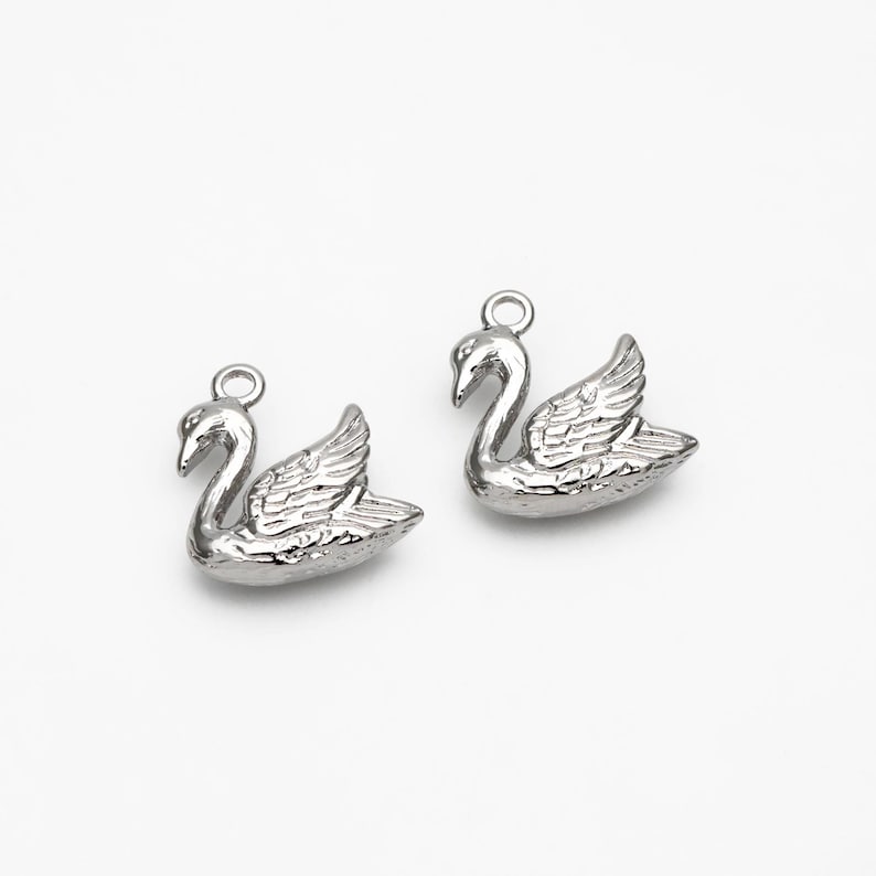May include: Two silver swan charms with a loop for attaching to a necklace or bracelet.