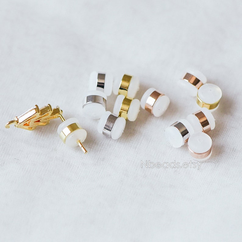 May include: Assortment of earring backs in gold, silver, and rose gold finishes. The backs are made of metal and have a clear plastic backing.