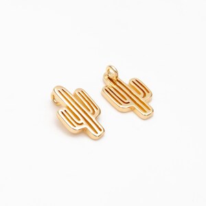 Op de afbeelding: Twee goudkleurige metalen cactusbedels met een lus om aan sieraden of andere knutselwerkjes te bevestigen.
