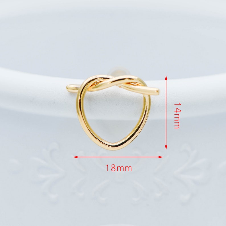 May include: Gold heart-shaped knot ring with a diameter of 1.8 inches and a height of 1.4 inches.