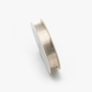 May include: A spool of silver-colored wire for jewelry making.