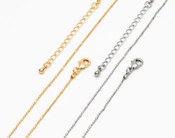 May include: Close-up of gold and silver necklace chains with lobster claw clasps and extender chains. The chains have a delicate, textured design. The background is plain white, highlighting the jewellery.