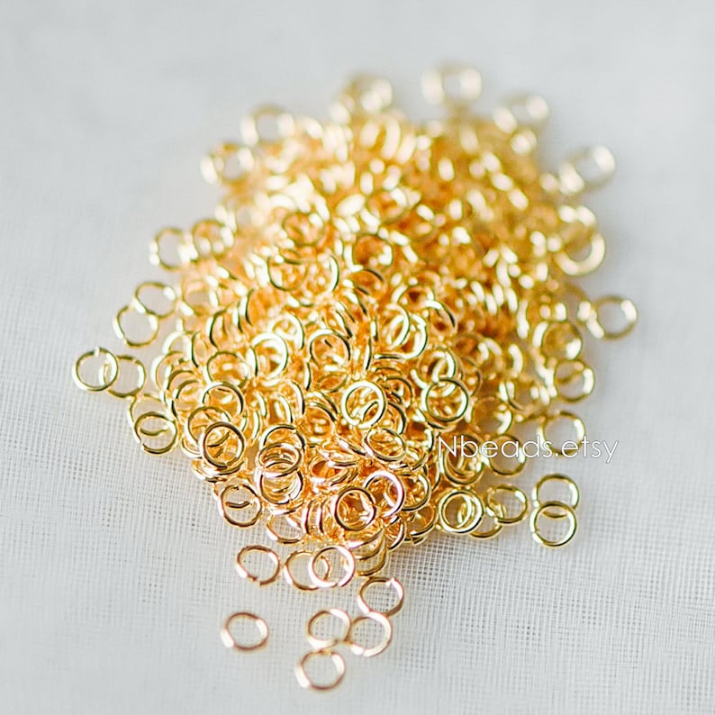 May include: A large pile of gold jump rings. The rings are small and round, and they are perfect for jewelry making.