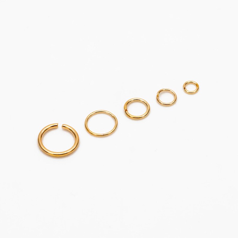 May include: Set of six gold-toned hoop earrings of varying sizes. The hoops are arranged in a line from largest to smallest.