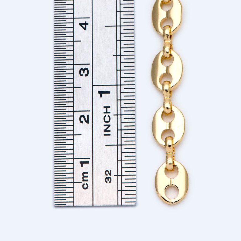 May include: A gold-colored chain with oval links, shown next to a ruler. The chain is approximately 4 inches long. The ruler displays both inches and centimeters for measurement. The chain links have a polished finish and are connected by small, round connectors.