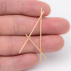 Puede incluir: Pendientes geom&eacute;tricos dorados con dos l&iacute;neas finas y rectas que se cruzan para formar una forma triangular.