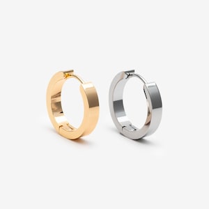 May include: A pair of hoop earrings featuring a smooth, polished finish. One earring is gold-toned, and the other is silver-toned. Both hoops have a hinged closure mechanism, showcasing a simple, circular design with a flat, wide band profile.