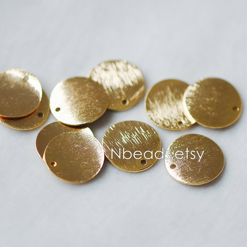 May include: A group of ten gold-colored metal round discs with a hole in the center. The discs have a brushed finish.