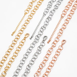 May include: Three chains in gold, silver and rose gold with lobster clasps. The chains are made of linked circles.