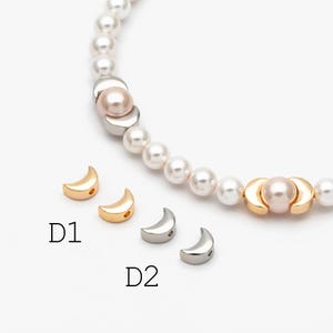 Peut inclure: Un bracelet de perles avec des perles en forme de croissant de lune dorées et argentées. Le bracelet présente des perles blanches, des perles en forme de croissant de lune dorées et argentées et un accent de perle rose. L'image montre également des perles en forme de croissant de lune en vrac étiquetées D1 et D2.