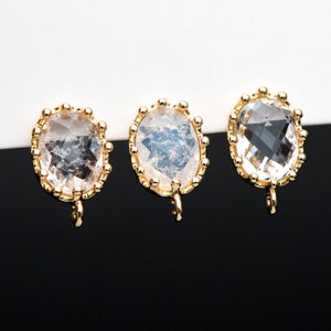 May include: Three gold-toned oval-shaped pendants with clear and iridescent crystal stones. Each pendant has a small loop at the bottom.
