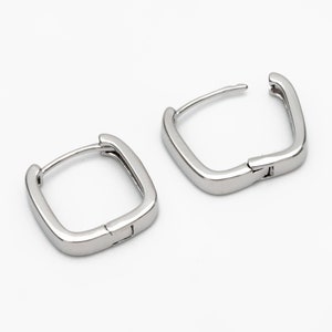Pu&ograve; includere: Un paio di orecchini a cerchio quadrati in argento. Gli orecchini sono in metallo e hanno una chiusura a cerniera.