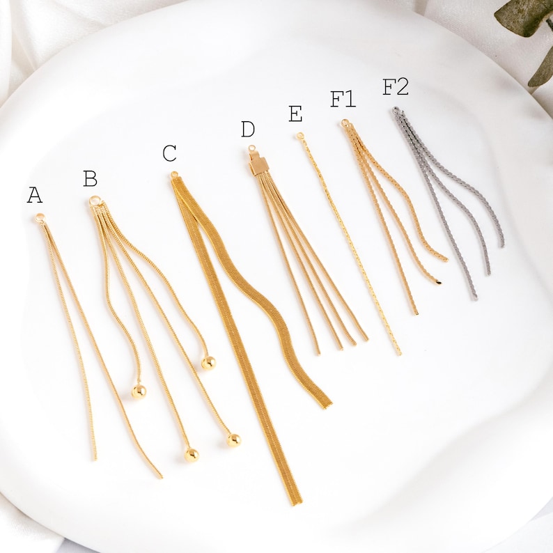 May include: Assortment of gold and silver chain earring components, labeled A through F2. The chains are various lengths and styles, including a single chain, a chain with three strands, and a chain with five strands. Some chains have small beads at the end.