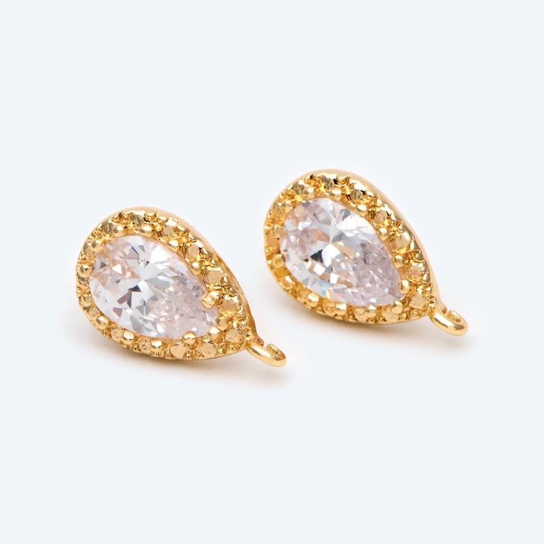 May include: A pair of gold-tone teardrop-shaped earrings with clear cubic zirconia stones.