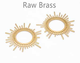 May include: Two gold-toned metal sunburst-shaped rings with a circular center. The text "Raw Brass" is written above the rings.