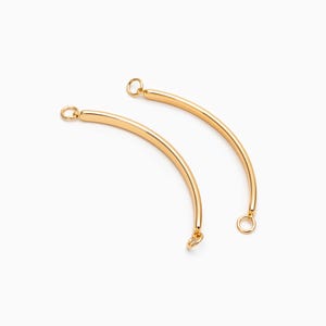 May include: Two gold-toned metal connector pieces for jewelry making. Each piece is a curved bar with a small loop at each end.
