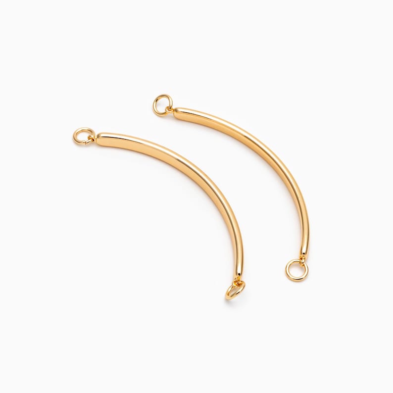 May include: Two gold-toned metal connector pieces for jewelry making. Each piece is a curved bar with a small loop at each end.