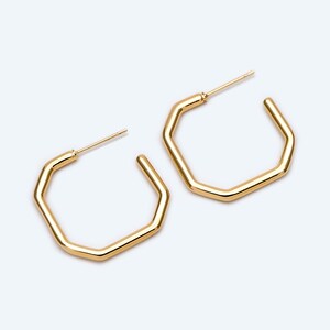 May include: A pair of gold octagon hoop earrings. The earrings are simple and elegant.