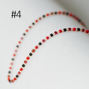 May include: A gold chain necklace with red and black square beads. #4