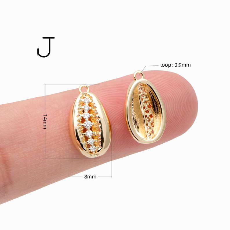 May include: Two gold-toned cowrie shell charms labeled J, each featuring a central row of clear cubic zirconia stones. The charms measure 14mm in height, 8mm in width, and have a 0.9mm loop for attachment.