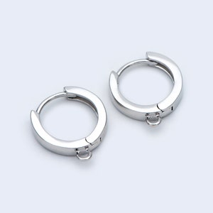 May include: A pair of silver hoop earrings with a small, dangling loop on each earring.