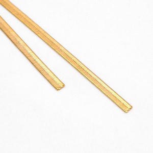 May include: Two gold snake chain necklaces of different lengths.