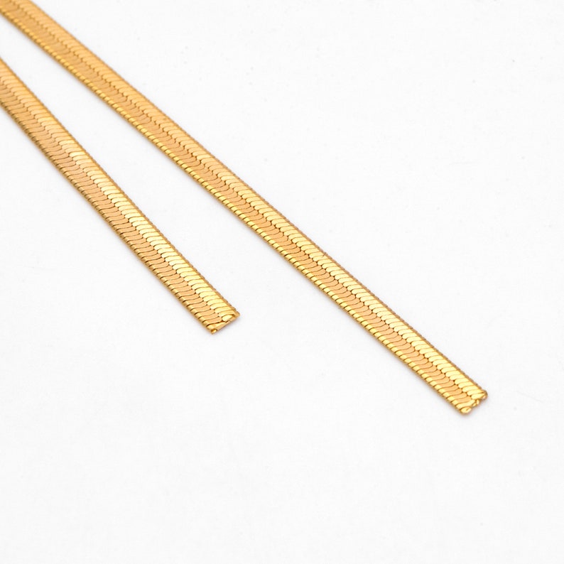 May include: Two gold snake chain necklaces of different lengths.
