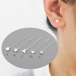 Può includere: Cinque orecchini pendenti in argento con ciondoli diversi: un cuore, una stella, un trifoglio, una farfalla e una stella. Gli orecchini sono mostrati su uno sfondo grigio con le lettere da A a E che etichettano ogni orecchino.