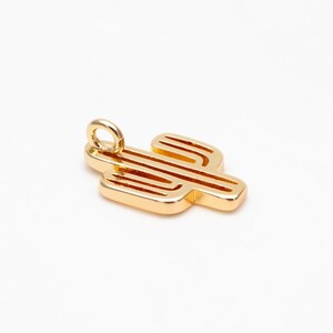 Op de afbeelding: Goudkleurige metalen hanger in de vorm van een cactus met een lus aan de bovenkant om aan een ketting of armband te bevestigen.